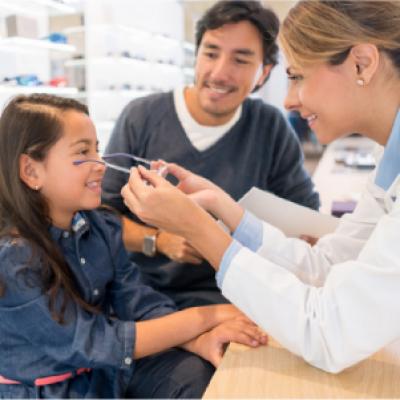 Young girl gets fitted for glasses with her father.