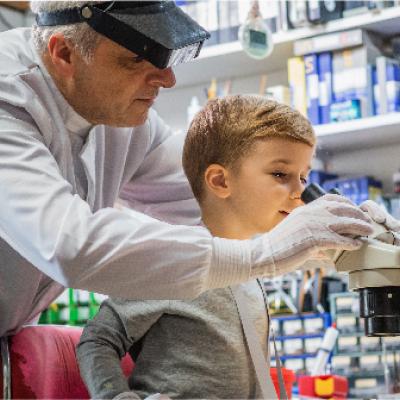 Scientist helps boy look through a microscope
