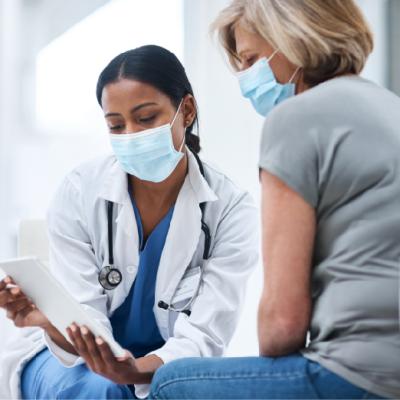 Photo of a young doctor using a digital tablet during a consultation with a senior woman.