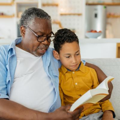 Elderly man and child reading a book together.