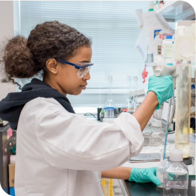 Young scientist wears safety goggles and holds test tube in lab.