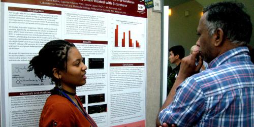 Two researchers stand in front of a poster presentation.