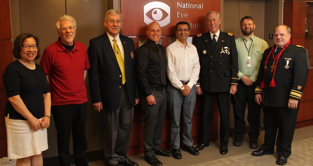 Hotaling, Bharti, and others in front of NEI logo