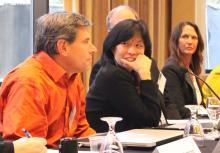 Two women panelists look at male colleague as he speaks