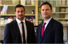 Two men in suits look at the camera