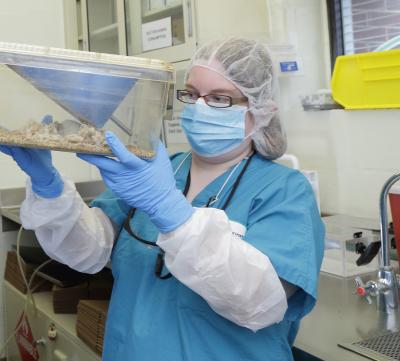 Hall holds up mouse cage in front of her.