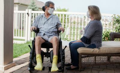 A woman sits and talks with a man in a wheelchair