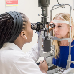 Doctor examines woman's eye with slit lamp test.