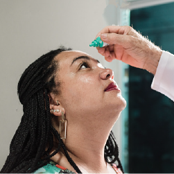 Doctor places eye drops in woman's eye.