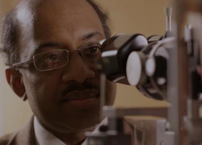 A doctor looks into a slit lamp