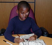 little boy with eye patch simultaneously writing. 