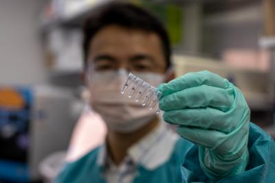 Man in a laboratory holding samples in a series of transparent wells. 