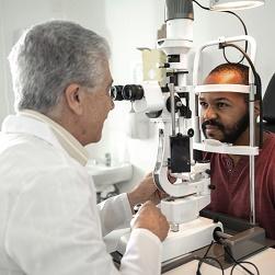 Un doctor examina con una lámpara de hendidura los ojos de un hombre.