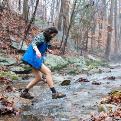 Woman crossing a stream in the woods