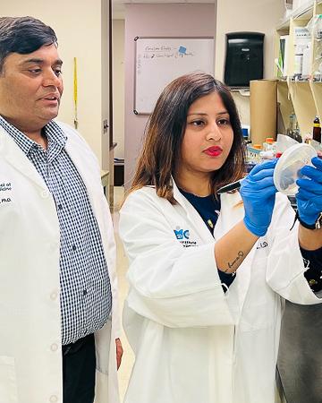 Scientists look at a plate of bacteria
