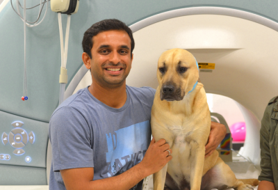 A man and a dog in front of an MRI scanner