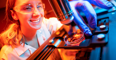 Madison Wilson holds microelectrode array under a microscope.