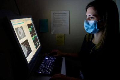Scientist examines scientific images on a screen in a dark room.