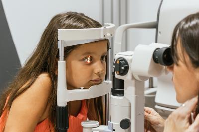 Doctor examines child's eye with a slit lamp.