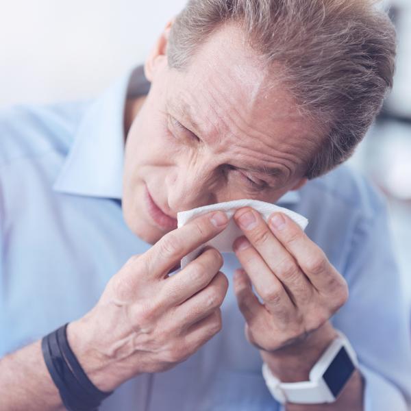 A man wiping his eye with a tissue