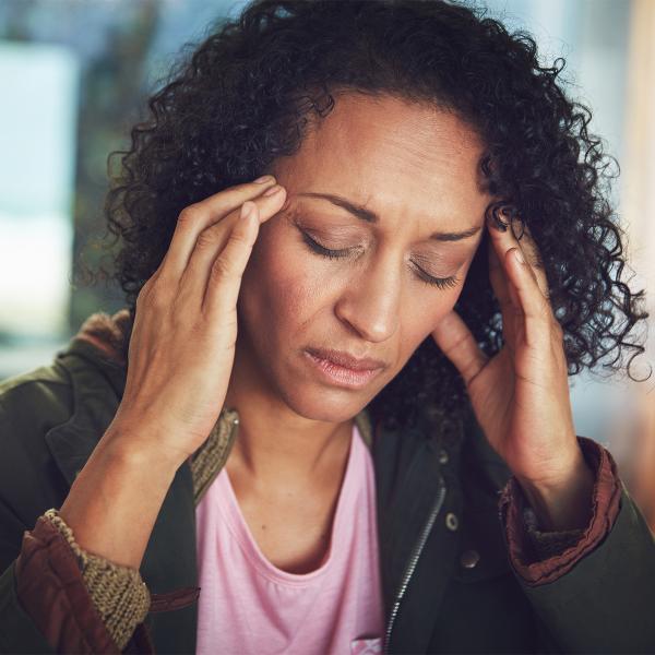 A woman rubs her temples in pain