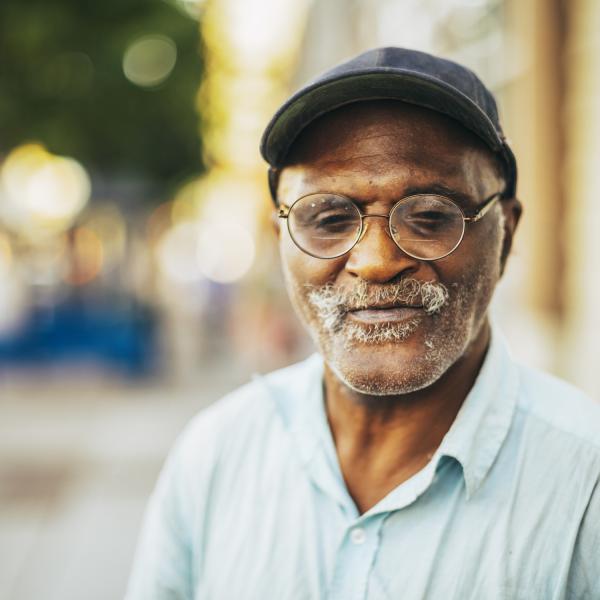 Portrait of a man with glasses on a street.