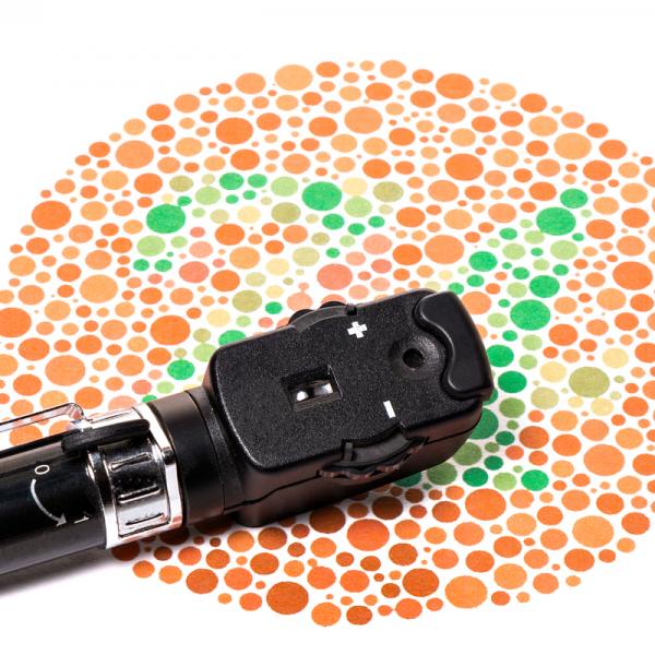 Orange and green dots on paper with an ophthalmoscope resting on top