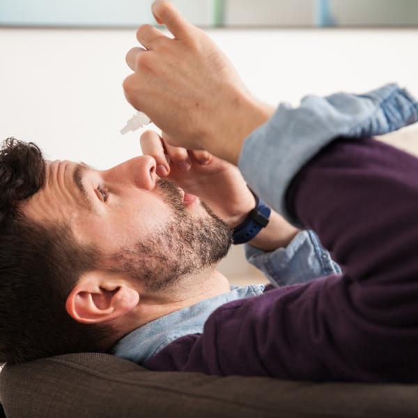 Person putting eye drops in their eyes.