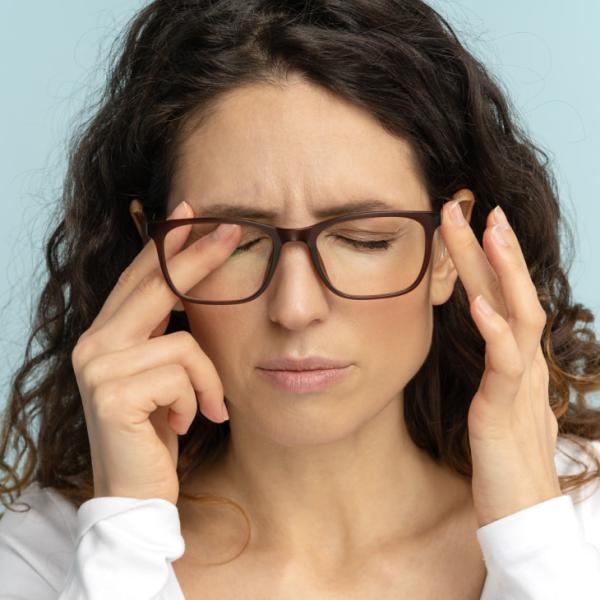 Una mujer con anteojos se frota los ojos.