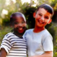 Two boys smile at the camera. Asymmetric dark spots block parts of the image, representing vision loss from diabetic retinopathy.