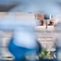 Scientist viewed through a laboratory shelf filled with bottles