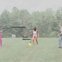 Three soccer players on a field. Center player looks down at the ball by her feet.