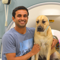 A man and a dog in front of an MRI scanner