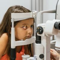 Doctor examines child's eye with a slit lamp.